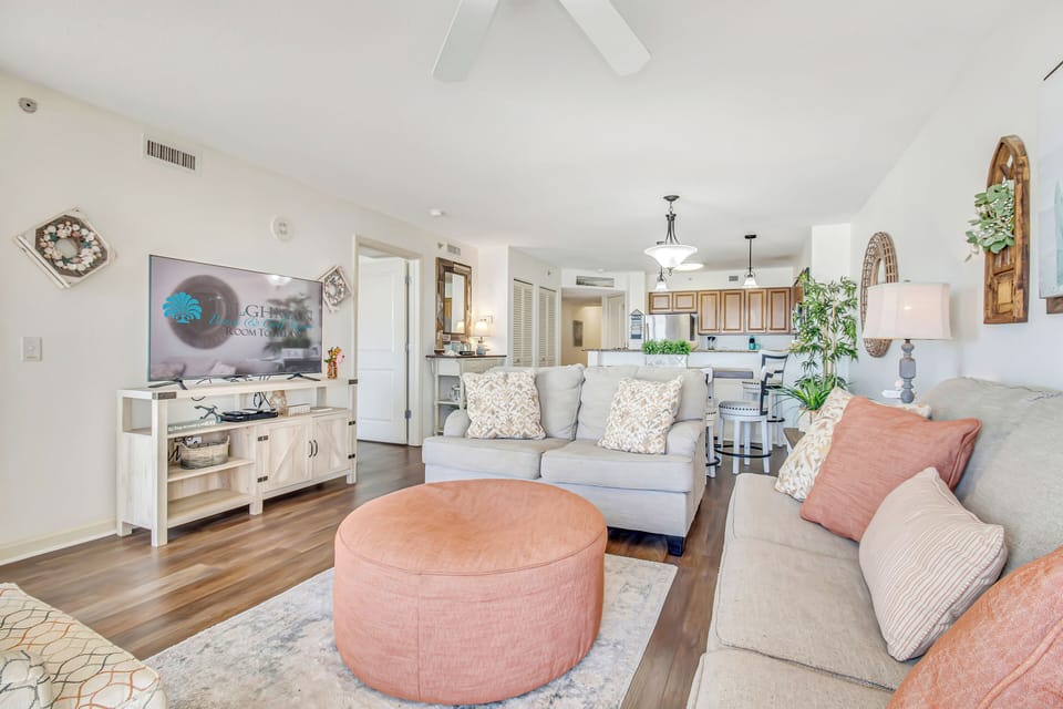 Relax in your open-concept living space with plush seating, modern amenities, and elegant coastal decor creating the perfect vacation atmosphere.