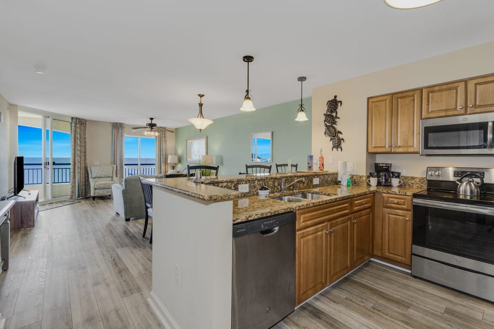 Your open kitchen flows into the living space, featuring granite counters and ocean views through floor-to-ceiling windows.