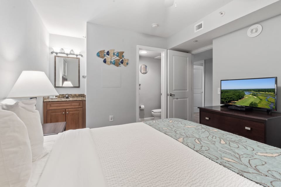 Unwind in your bright, contemporary bedroom featuring a comfy bed, entertainment center, and ensuite bathroom for ultimate convenience.