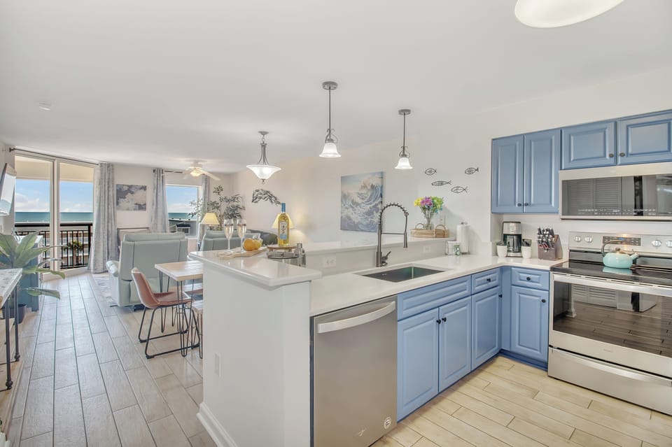 Your coastal kitchen features blue cabinets and gleaming countertops, with ocean views flowing through to your dining space.