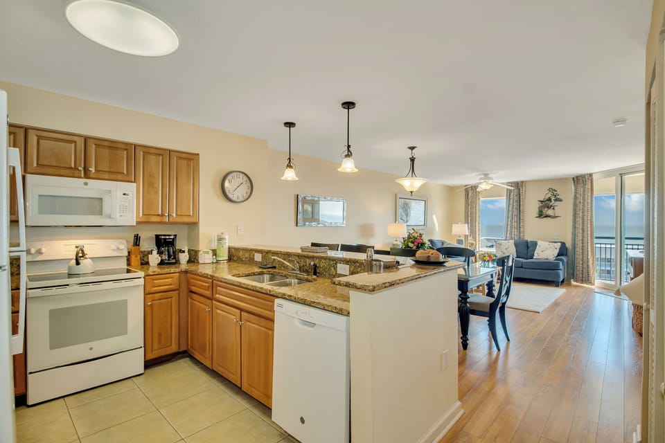 Your spacious kitchen features granite countertops and modern appliances, flowing seamlessly into a bright living area with ocean views.