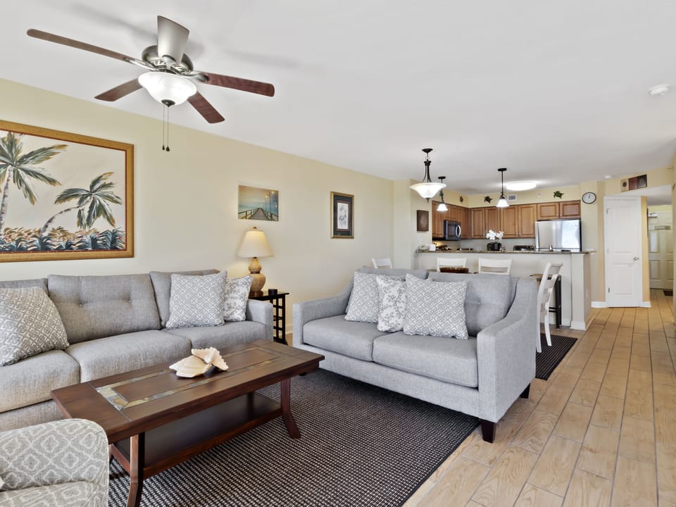 Relax in your spacious living area with plush seating, tropical artwork, and an open floor plan connecting to your fully equipped kitchen.