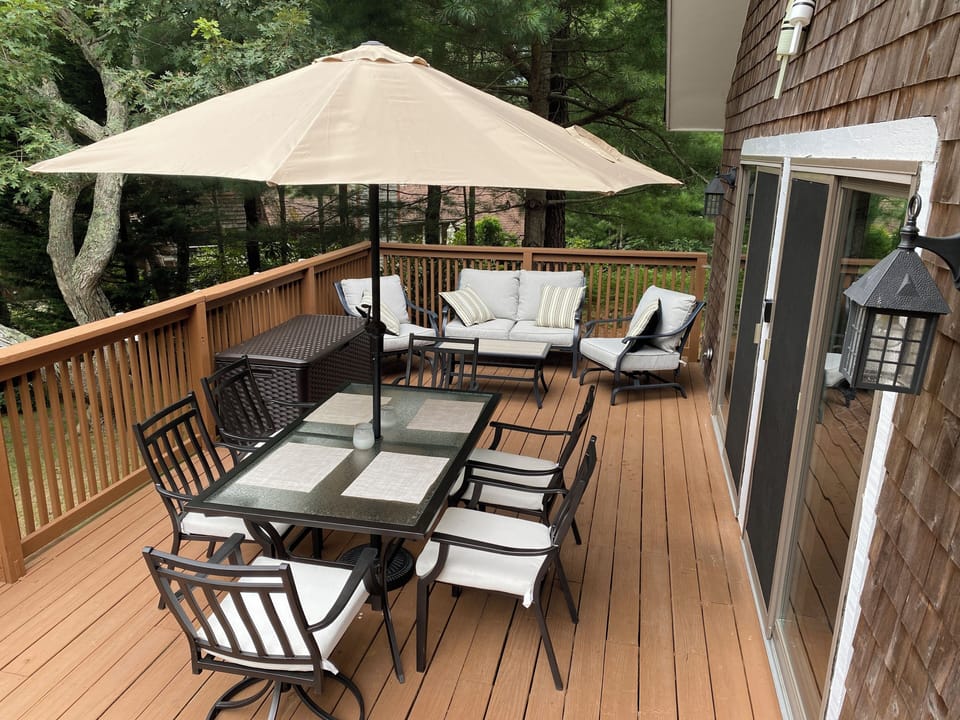Front deck with dining table, sitting area, and grill. 