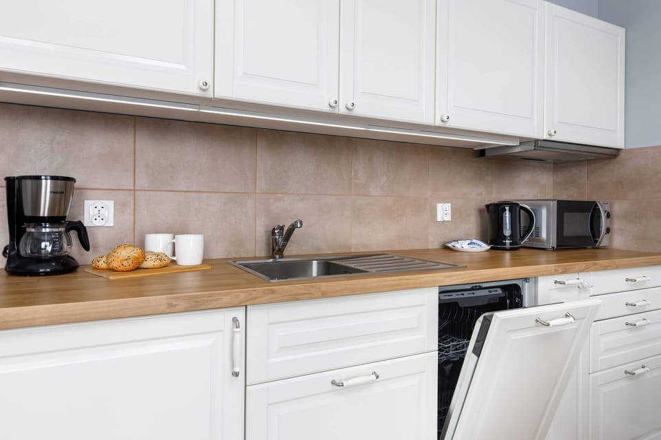 A modern kitchen counter featuring a kettle and microwave. The clean design emphasizes practicality and style.