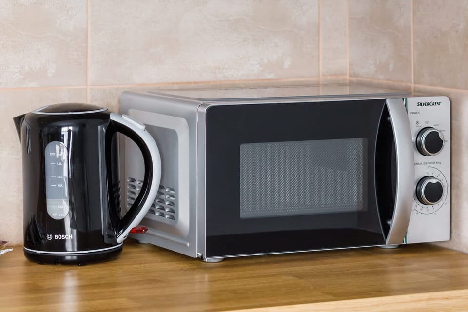 A sleek microwave and kettle placed on a spotless countertop. The clean, modern design emphasizes functionality and style.