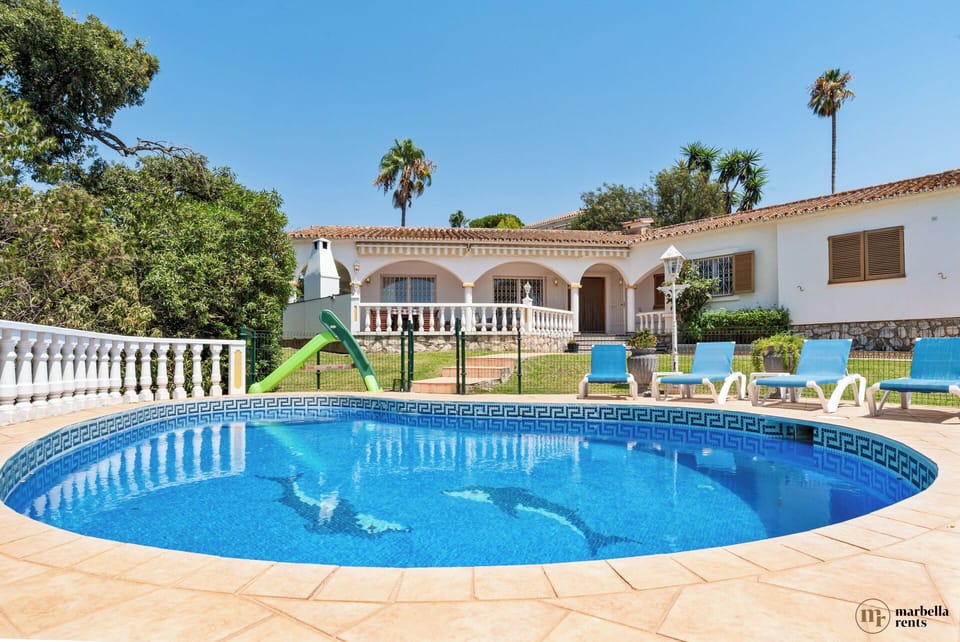Fully fenced pool with sun loungers.