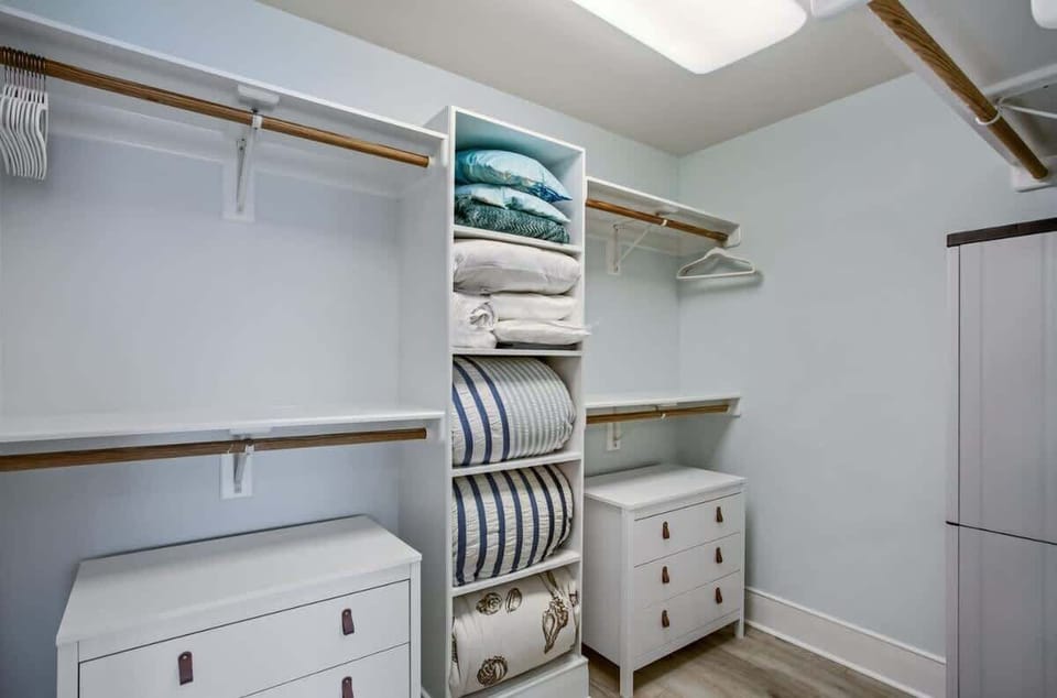 This beautifully organized walk-in closet features ample shelving, stylish white dressers, and plenty of hanging space. With a clean and modern design, it's the perfect space to keep your wardrobe and linens neatly stored!