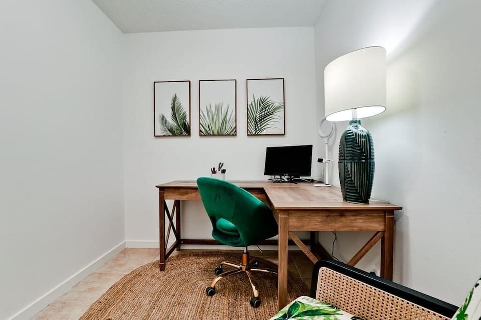 The dedicated workspace features a desk, monitor, rolling chair, and arm chair. French doors ensure privacy and sound control. 
