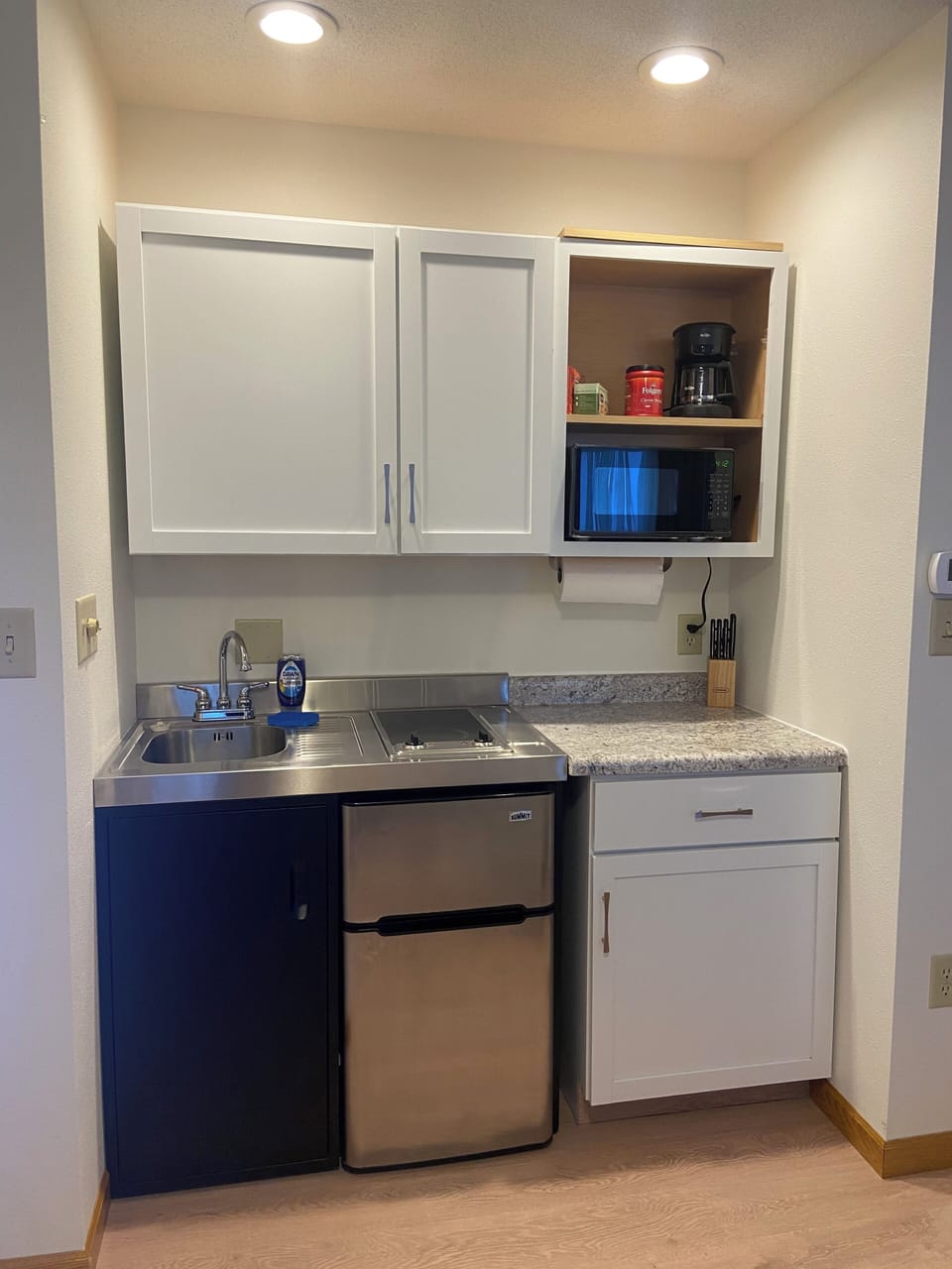 Kitchenette with mini fridge, sink, and two burner stove top. 