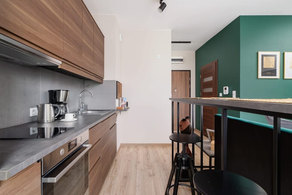 A close-up of the kitchen with sleek, modern wooden cabinetry and stainless steel appliances. The countertop is clutter-free and minimalist.