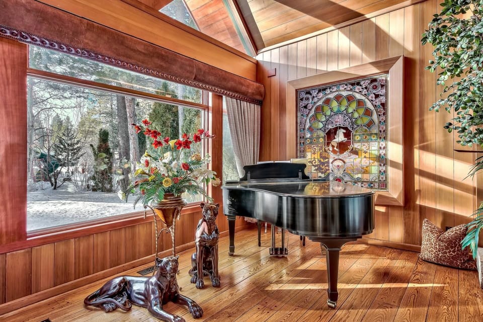 The great room is dominated at its northern end by the granite boulder fireplace, Grand Piano, and Pool table with a Lakeview window.