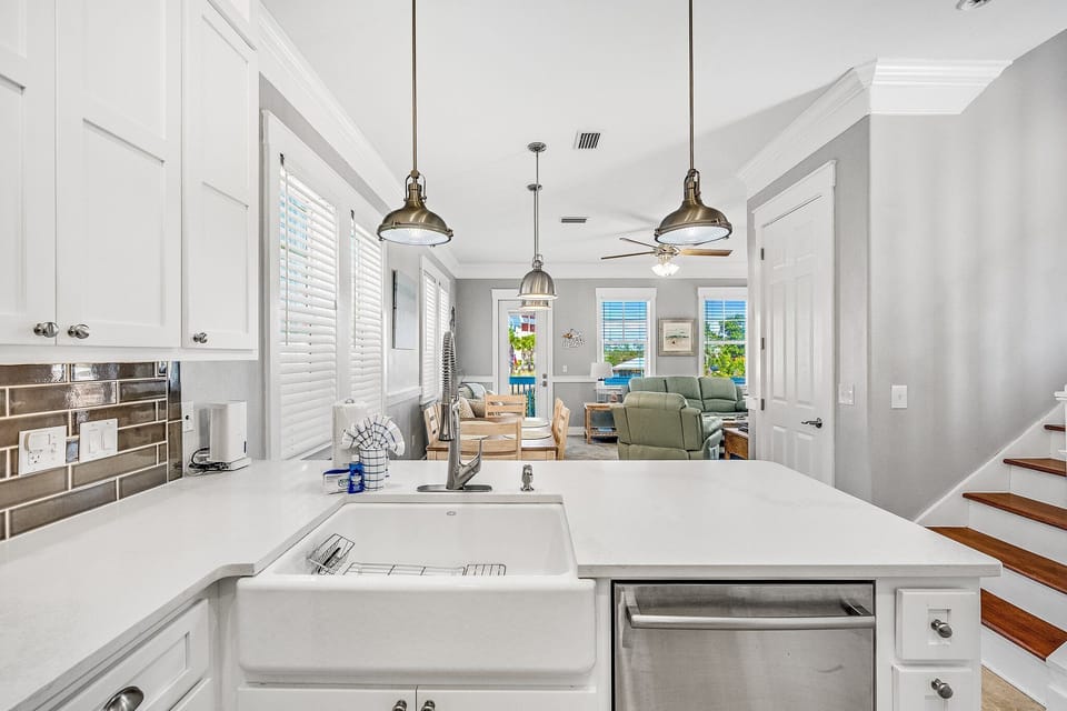 Your gourmet kitchen flows seamlessly into the bright living space, where white countertops and pendant lighting create the perfect backdrop for cooking.
