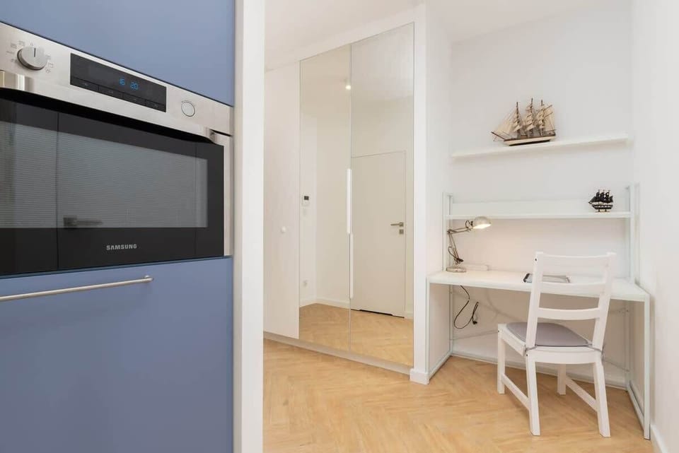 A modern kitchen space with a built-in oven and microwave, featuring light-colored cabinetry.

