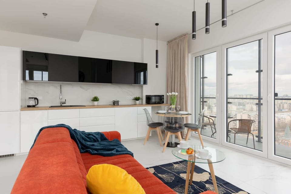 A cozy living room with a fold-out sofa, perfect for relaxing or hosting guests. The open-plan layout connects seamlessly to the modern kitchen in the background.