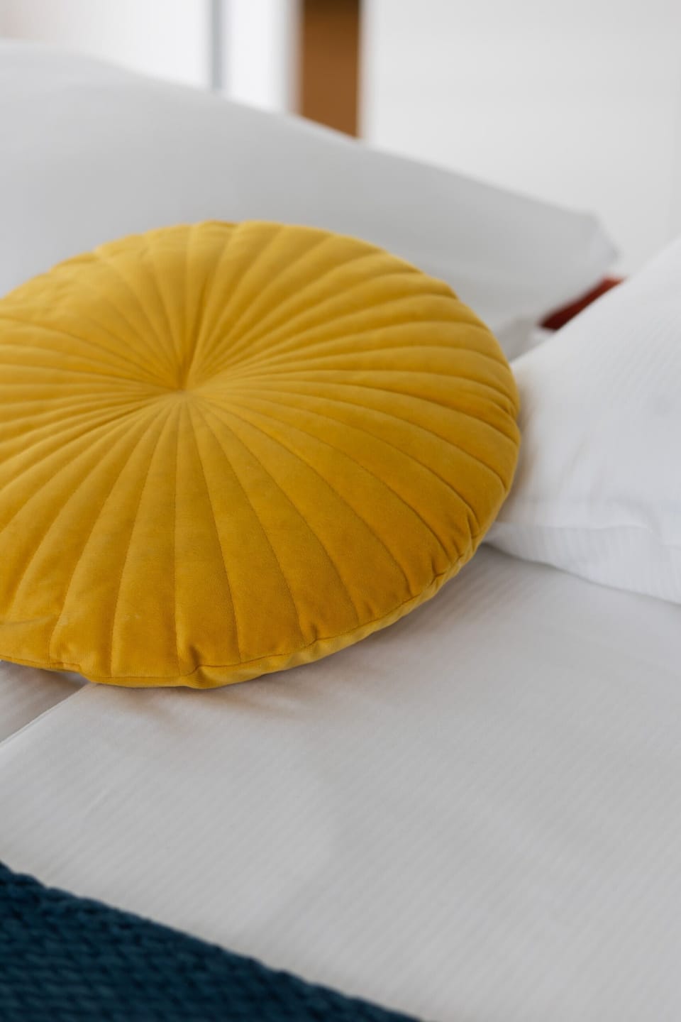 A close-up of a stylish mustard-yellow pillow on a textured blue throw. The vibrant color combination adds warmth and comfort.