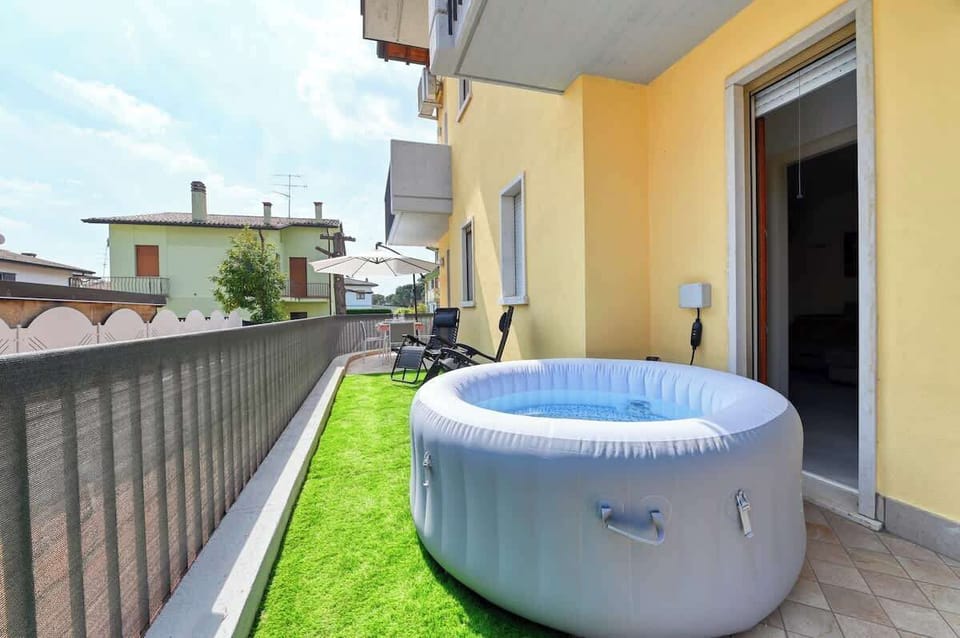 Giardino esterno (NON RECINTATO) con jacuzzi privata, tavolo da pranzo ed ombrellone, sdraio a gravità 0 con erba sintetica