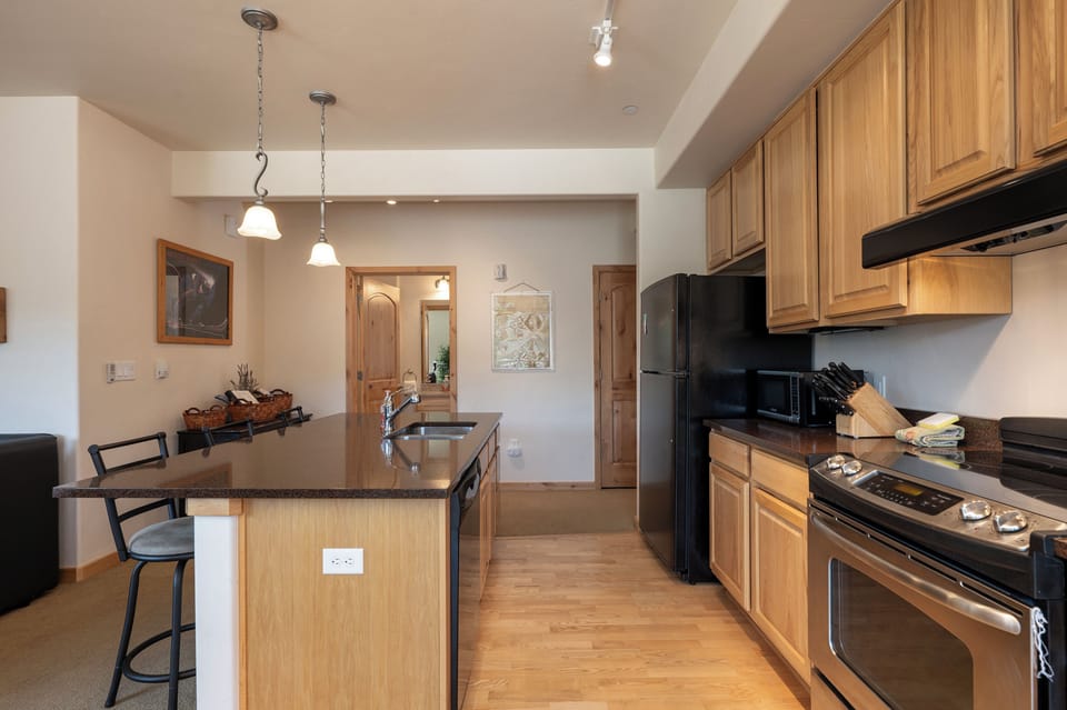 Your spacious kitchen features warm wood cabinets, granite countertops, and modern black appliances - perfect for preparing meals during your stay.
