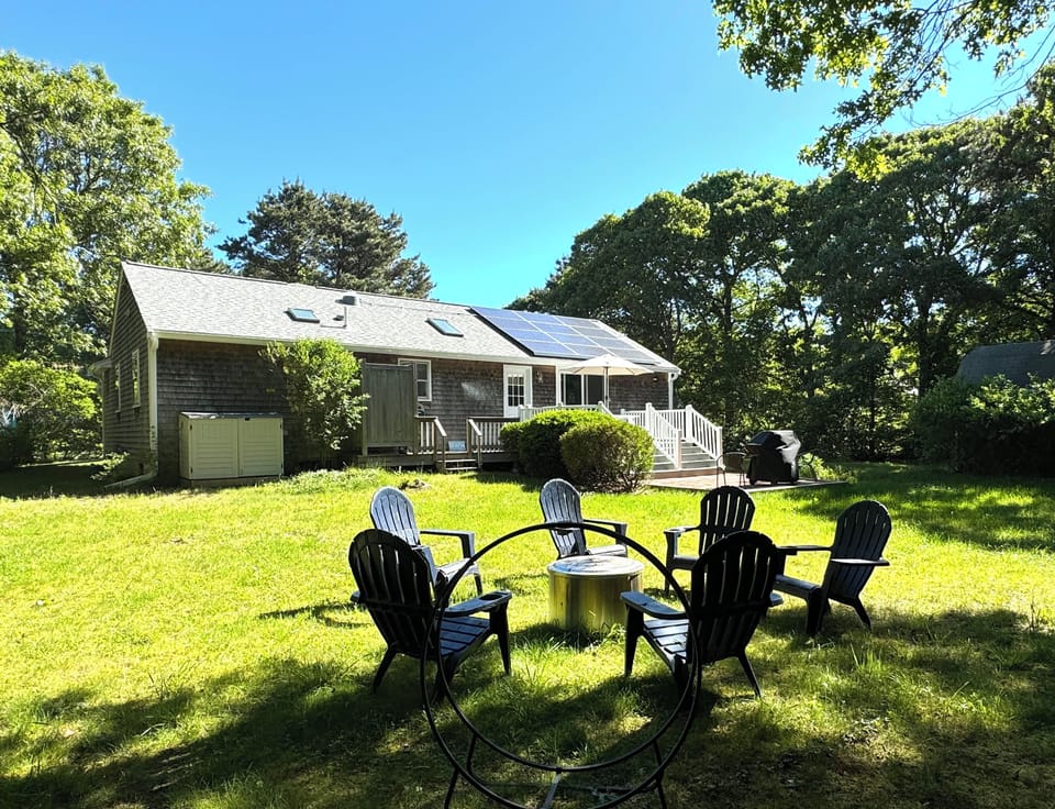 Spacious backyard with firepit, view to outdoor shower, deck, umbrella and bbq
