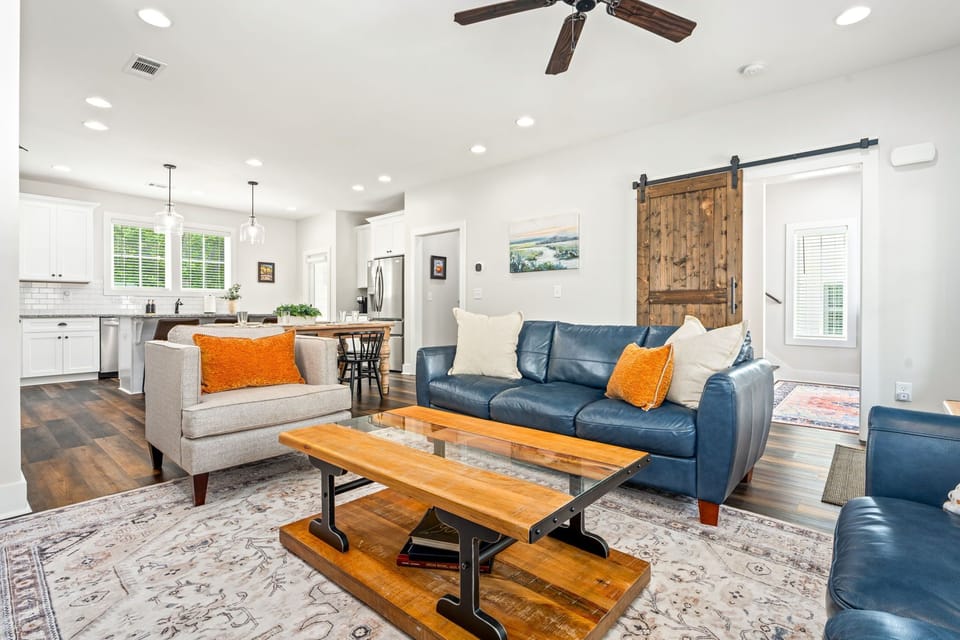 Comfortable leather couches, barn door gives privacy for flex room and bedrooms