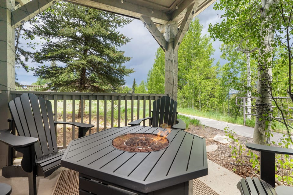 Covered patio with 4 Adirondack chairs & a firepit for relaxation.