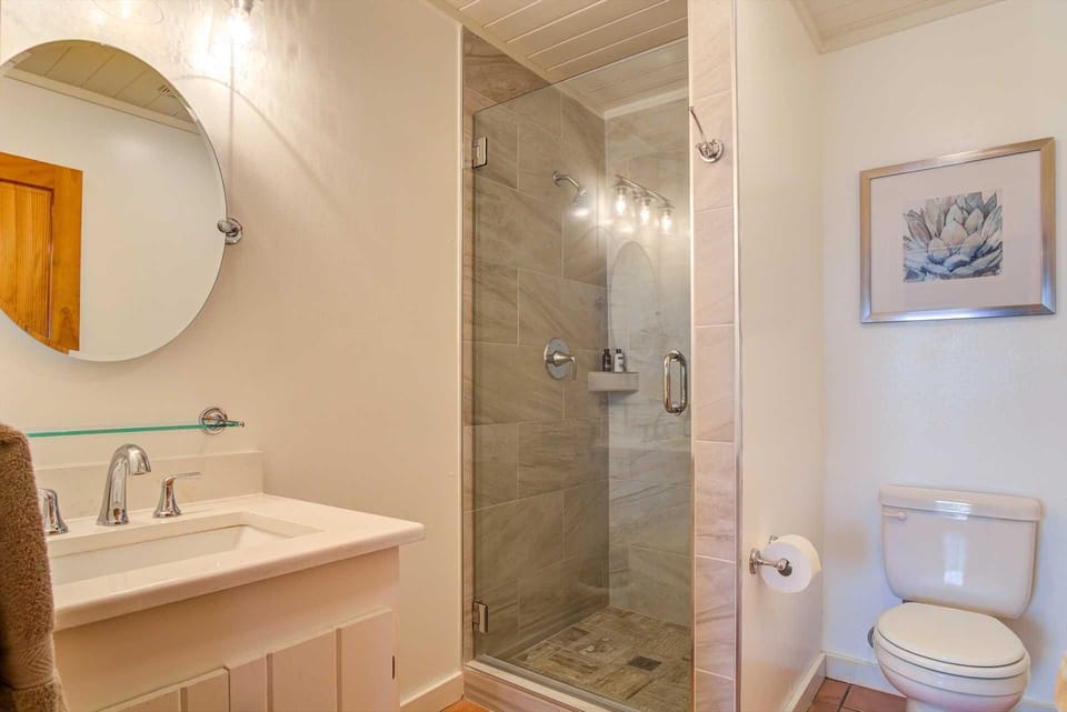 The spotless full bath in the house here includes a glass-door shower stall and clean linens.