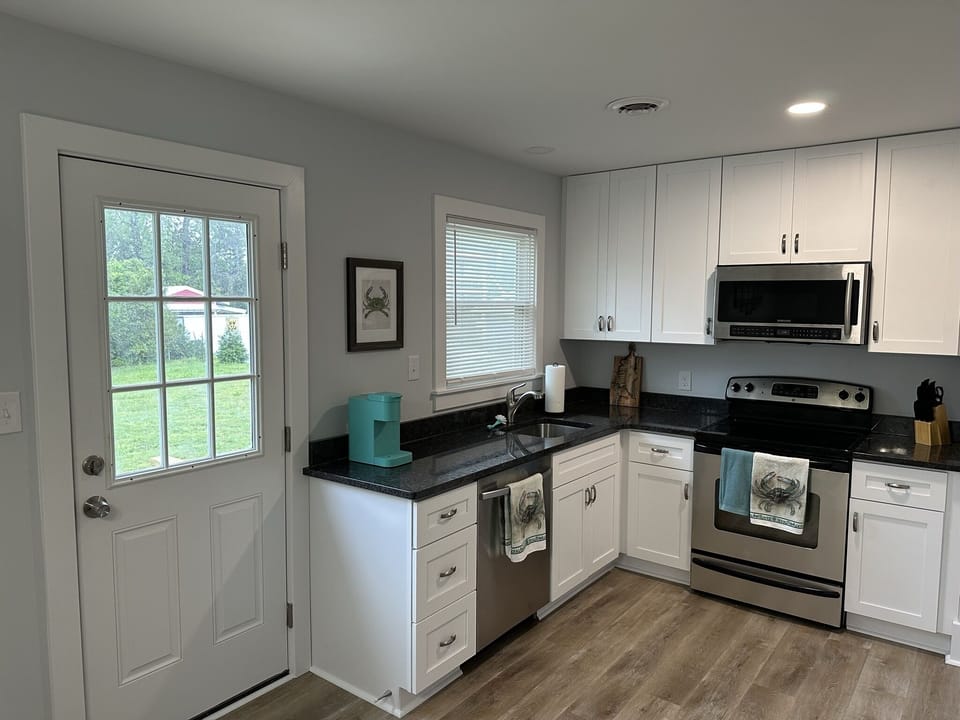 Full kitchen with access to back patio, grill, and outdoor seating. 