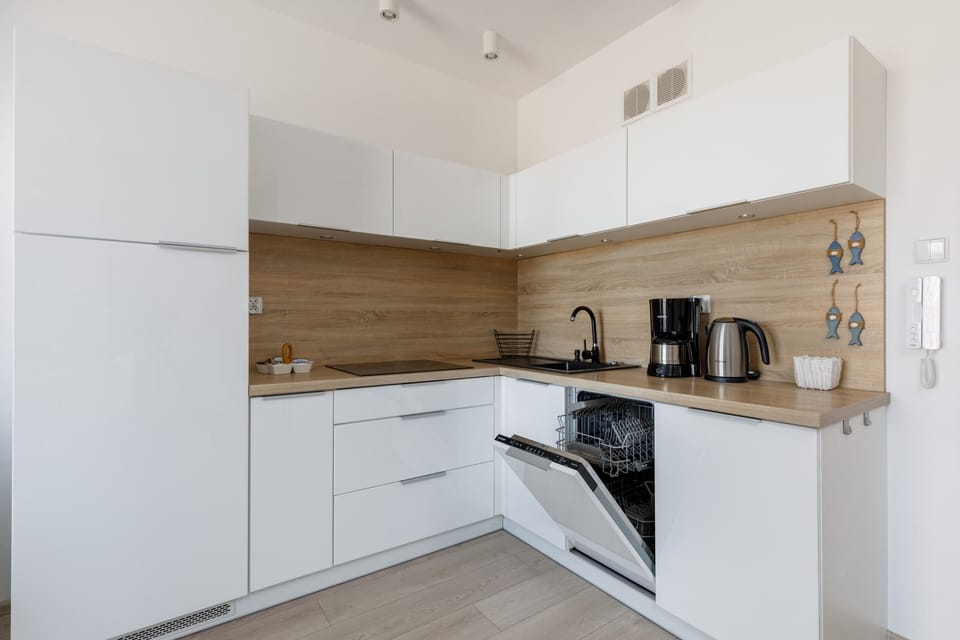 A fully equipped kitchen with white cabinets, wooden countertops, and a clean design.
