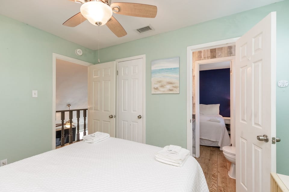Drift off in your serene mint-green bedroom with coastal artwork and gentle ceiling fan breezes creating the perfect sleep sanctuary.