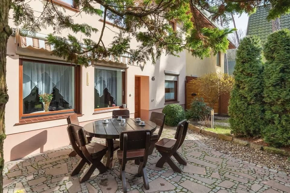 A patio with a table and chairs surrounded by lush greenery, ideal for outdoor dining.