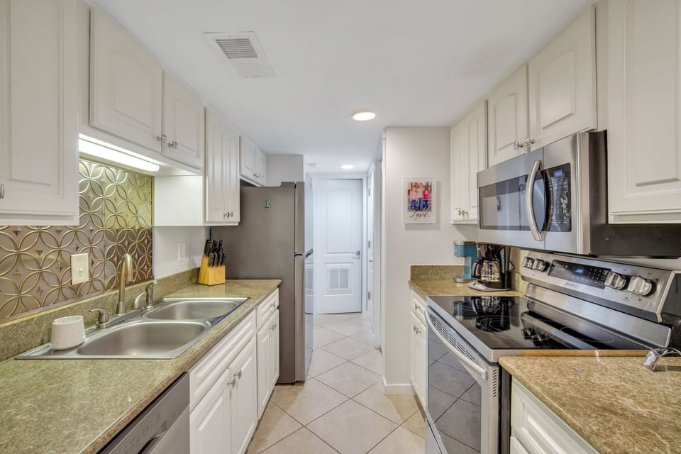 The kitchen features stainless steel appliances, pantry storage, and a coffee maker.