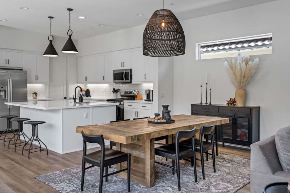 Gather around the dining table beside a sleek kitchen w/ bar seating & pendant lighting