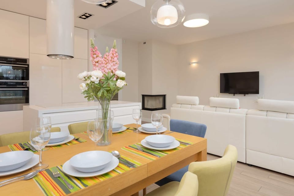 A dining area set for four with a wooden table, colorful chairs, and a centerpiece of fresh flowers.
