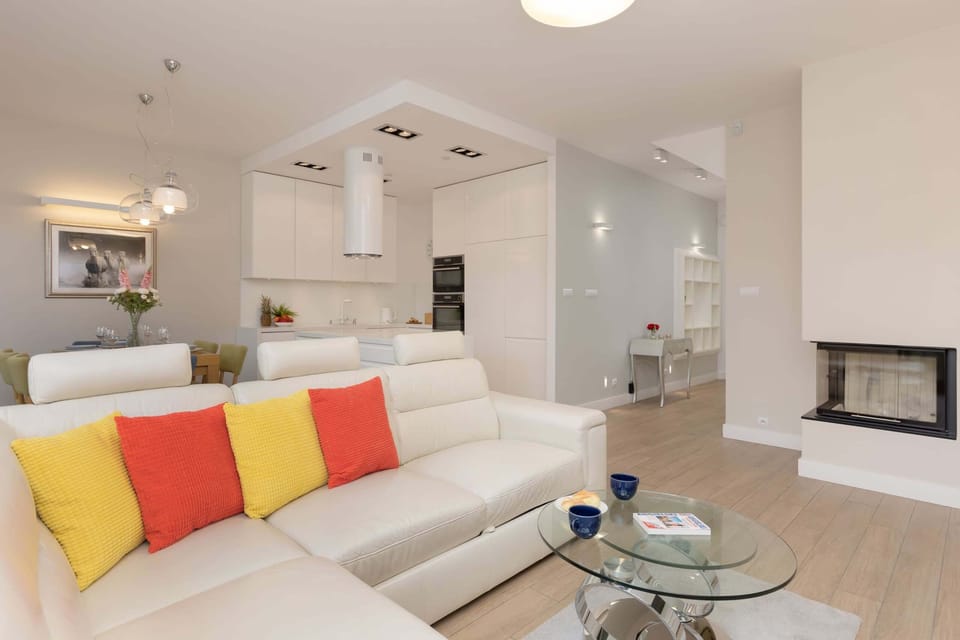 A living room with a white sectional sofa, colorful cushions, and a fireplace, creating a welcoming ambiance.
