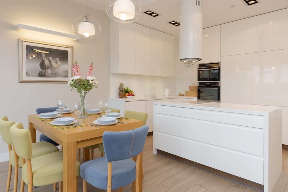 A modern dining and kitchen area with vibrant chairs and a functional open-plan layout.
