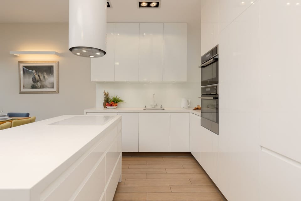 A modern kitchen with white cabinets, ample storage, and a sleek design.
