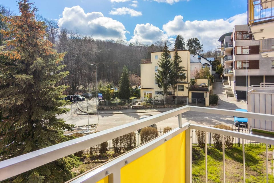 A balcony view overlooking a landscaped area with trees and residential surroundings.
