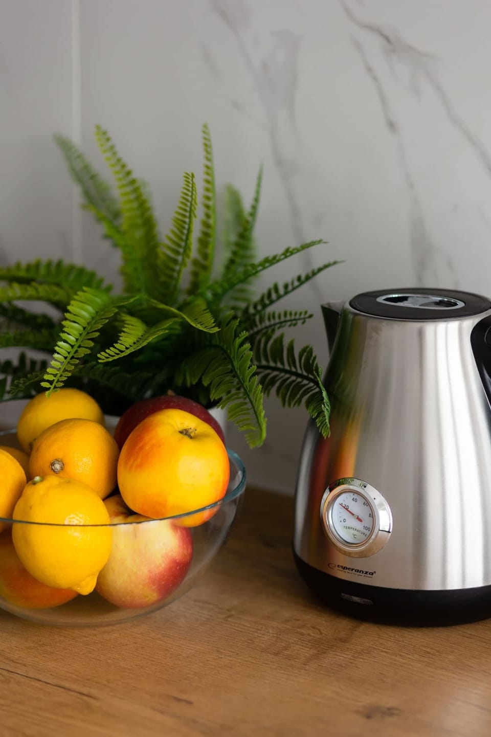 A close-up of a decorative fruit bowl and kettle on the countertop, adding a homely touch to the kitchen.

