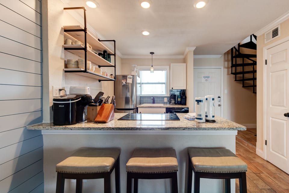 Cook your favorite meals in this modern kitchen featuring granite counters, stainless appliances, and stylish open shelving for all your culinary adventures.
