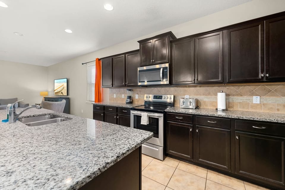 Sleek kitchen view w/ dark cabinetry, island seating & modern finishes.
