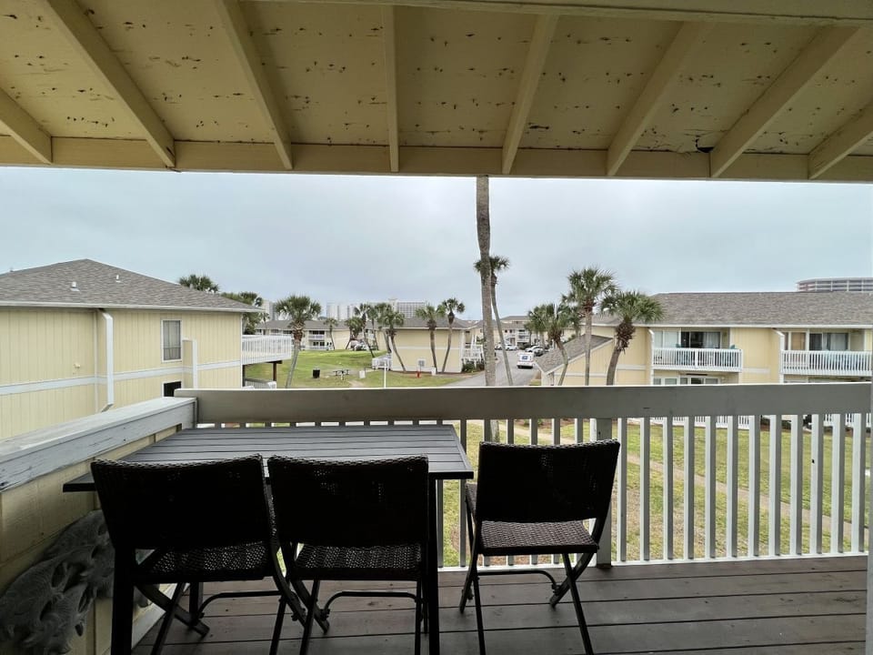 Unwind on your private covered balcony with comfortable seating, overlooking tropical palms and coastal neighborhood charm.