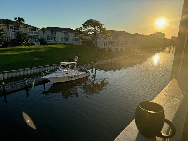 Waterfront sunrise view from balcony with canal, boats, and peaceful residential setting.