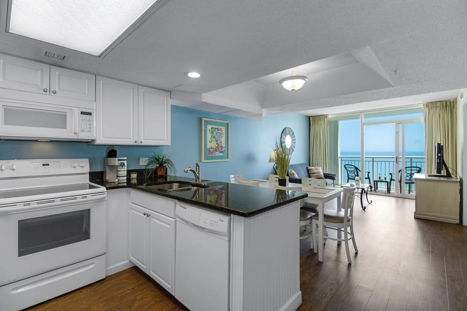 Cook up a meal or enjoy a coffee in this fully equipped kitchen, featuring modern appliances and a spacious counter. With a dining area that opens to ocean views, it’s the perfect spot to relax and enjoy your stay.