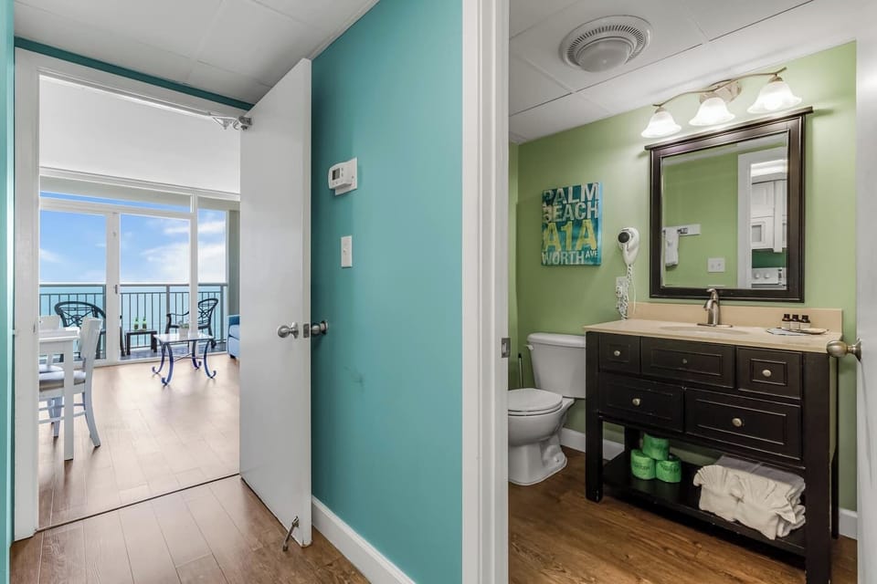 Bright and inviting bathroom with modern fixtures and a coastal flair! Just steps away, enjoy the open floor plan leading to breathtaking ocean views from the balcony. 
