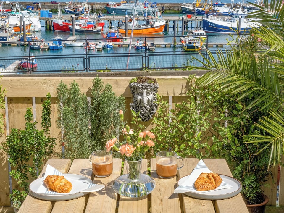 You could throw a pebble into the harbour from this cosy little patio. Hear fishermen on their boats and smell the salty air | Old Quay, Newlyn