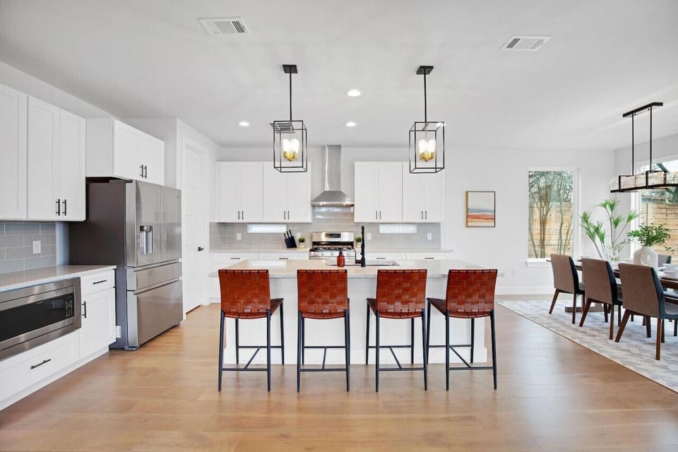 Prepare meals in this modern, fully-equipped kitchen featuring stainless steel appliances and a spacious island with bar seating. The open layout makes it easy to cook and entertain, ensuring a delightful culinary experience during your stay.