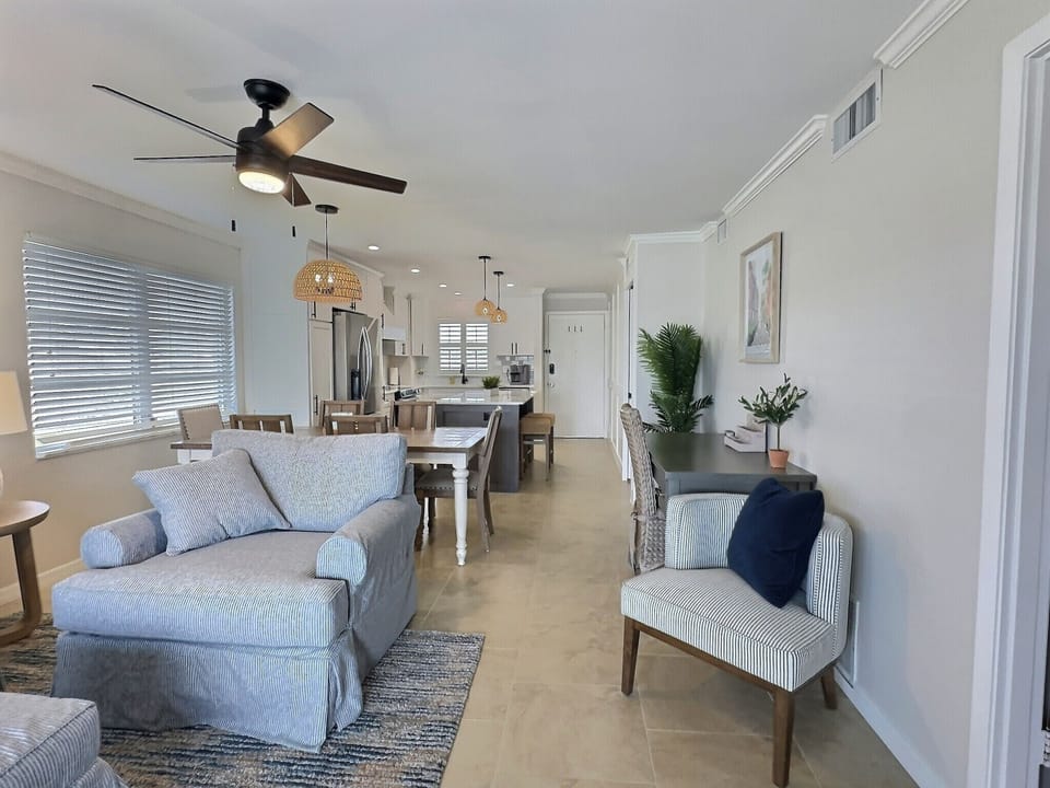 Living room featuring sofa, accent chair, and ceiling fan with views toward dining area