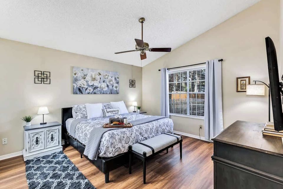 Spacious master bedroom with en suite bathroom, platform king bed with comfortable bedding, walk in closet, ceiling fan, matching nightstands, dresser, 55" HD TV, His/Her vanities and luggage rack.