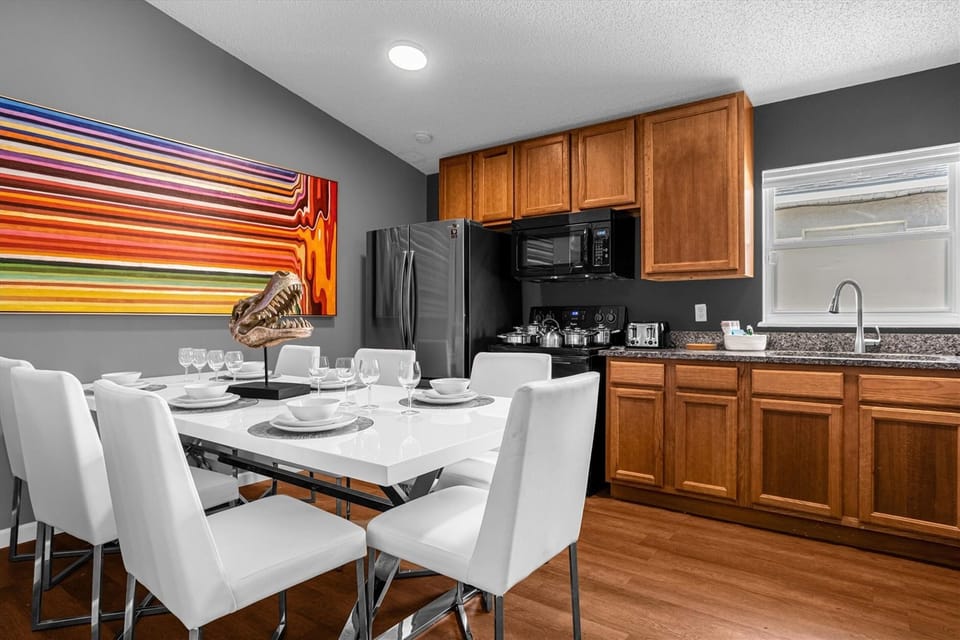 Modern kitchen and dining area with wooden cabinetry and a colorful wall art.