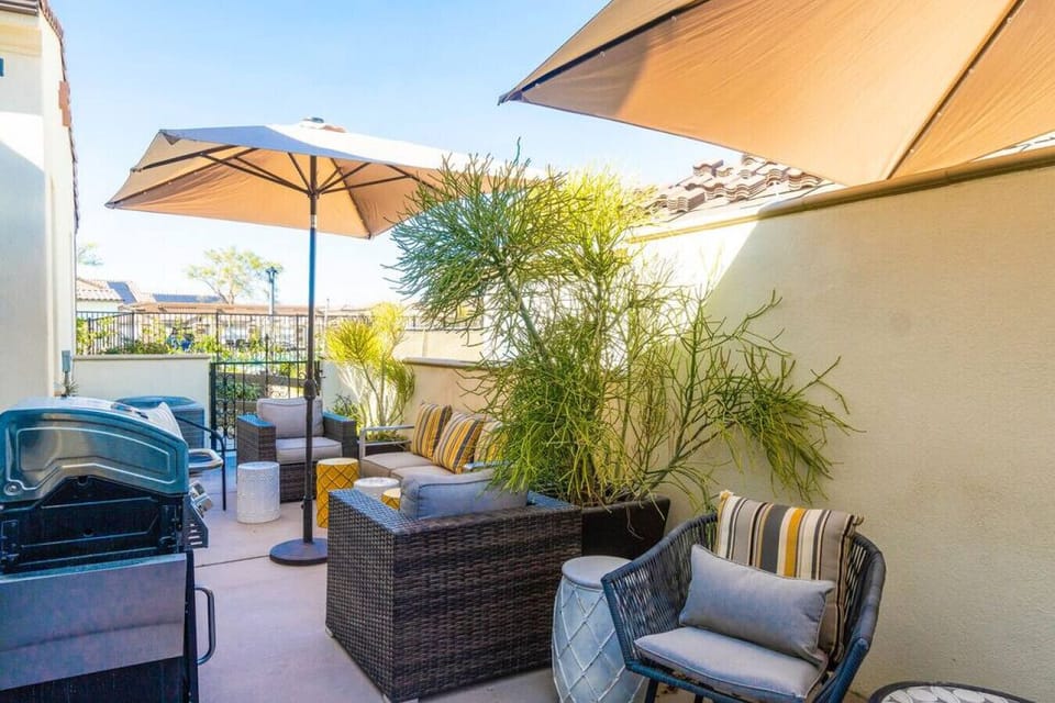 Cozy outdoor lounge w/ umbrella shade, seating & greenery for laid-back afternoons