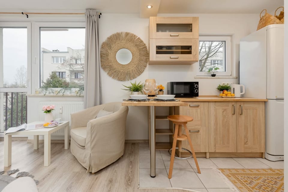 A compact kitchen with light wooden cabinets, a stainless-steel sink, and a white gas stove, maintaining a simple and functional design.

